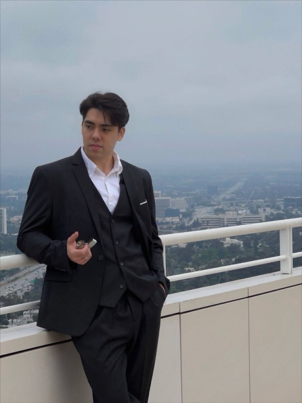 Matthew Stevens in a black suit on a rooftop above a misty city